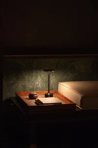 Cozy bedroom with a wooden headboard, a nightstand with two books, and a lamp providing soft lighting