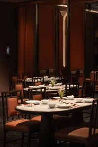 An inviting restaurant with dining tables, chairs, and table settings, creating a warm atmosphere for guests to enjoy meals