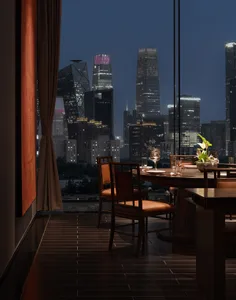 A dining area in a restaurant with a large table, wooden chairs, and wine glasses, creating a sophisticated and inviting atmosphere