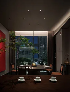 A dining area in a restaurant with a large wooden table set for guests, surrounded by chairs and potted plants, creating a sophisticated and inviting atmosphere