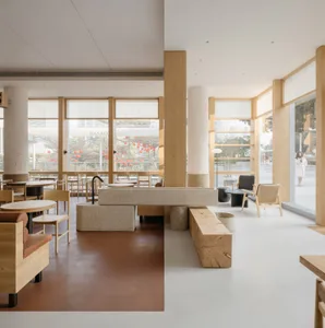 Open modern restaurant interior with wood flooring, chairs, and dining tables, well-lit with natural and artificial light