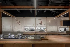 A clean and organized kitchen with a counter featuring various items on display, including cups, bowls, and bottles, in a professional environment