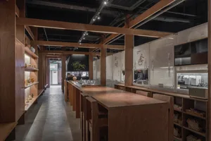 Industrial kitchen with wooden floors and walls, featuring chairs and dining tables, with a clean and organized atmosphere