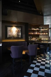 A modern bar area with a long counter, multiple bottles, and chairs, creating a stylish and inviting atmosphere