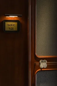 A warm and inviting Asian-style interior space with a wooden door featuring a small window and a gold sign, set against a neutral background