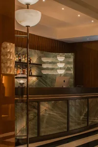 A casual bar area with a counter featuring a computer monitor, bottles, and cups, set in a restaurant with a comfortable atmosphere