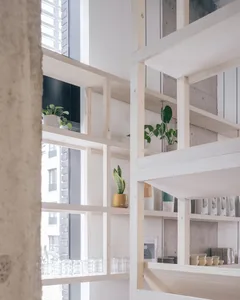 A clean and inviting interior space with wooden shelves and cabinets, surrounded by potted plants and decorative vases