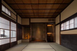 Asian-style living area with wooden floors and walls, featuring a tatami mat, table, chairs, and vase in a calm and serene atmosphere