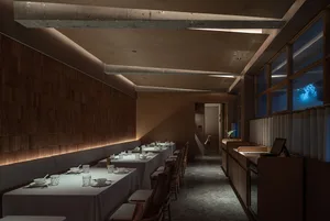 A well-lit restaurant dining area with a long table and multiple chairs, creating a welcoming atmosphere for guests