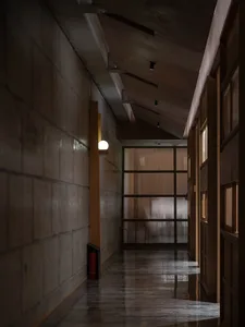 Empty hotel hallway with a concrete floor, glass doors, and two chairs for seating