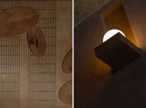 A wooden table with three wooden bowls and a metal light fixture mounted on a wall in a possibly kitchen or dining area setting