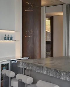 Modern kitchen area with a countertop bar, stools, and bottles, featuring a stylish and functional design