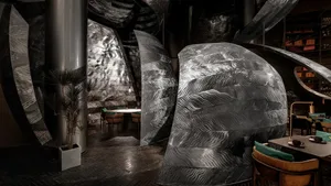 Modern dining space with a metal sculpture, a dining table, and chairs in a contemporary setting