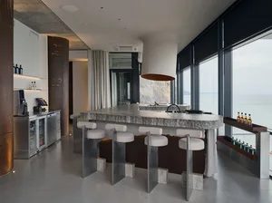 Open modern kitchen and dining area with a large island, stools, dining table, chairs, and natural light from a large window