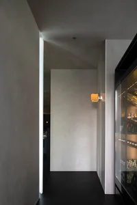 A cozy bar interior with a refrigerator in a corner, surrounded by walls and stocked with various bottles