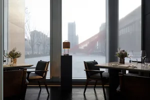 A bright and inviting restaurant interior with glass walls, modern furniture, and natural light from large windows