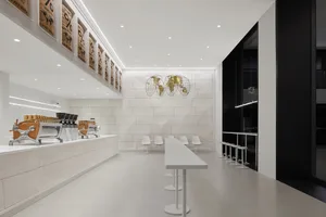 Empty restaurant interior with a large white countertop, chairs, and two dining tables in a clean and well-lit space