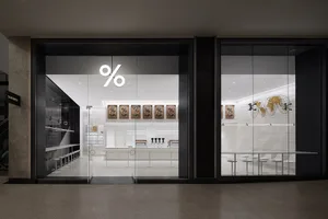 A modern cafe with a black and white theme, featuring a large glass window, tables, chairs, and bottles on display, creating an inviting and comfortable atmosphere