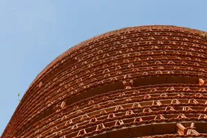Exterior photo of a modern building with a unique brick design, featuring a mix of red and brown bricks, in a warm and earthy color palette
