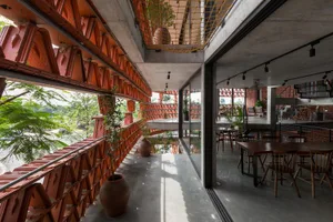 A restaurant interior with red brick walls, multiple tables, chairs, and potted plants, creating a warm and inviting atmosphere