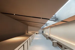 Empty modern room with a long countertop and benches, well-lit and minimalist in design