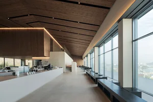 Open restaurant interior with wood flooring, large windows, and natural light, featuring dining tables, chairs, and table settings