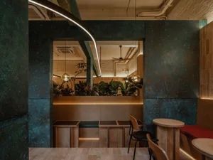 Modern restaurant interior with marble walls, tables, chairs, and a bar counter, surrounded by potted plants