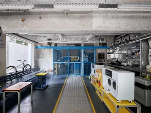Industrial open space with a yellow walkway, benches, and bicycles, showcasing the interior design and layout of the building