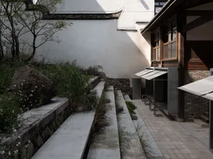A serene building with a stone exterior, two wooden benches, and a peaceful atmosphere