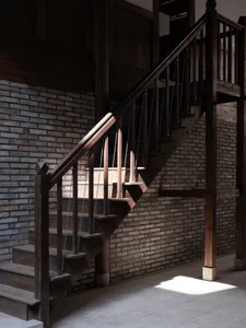 A dimly lit stairwell in a brick building with a wooden staircase and rustic details