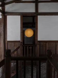 Old wooden building with a staircase leading to another level, lit by two lights on either side