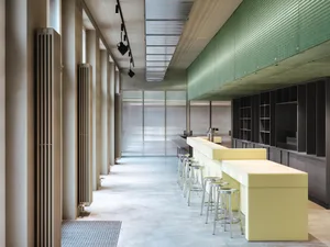 Modern restaurant interior with a long bar counter, stools, chairs, and warm lighting