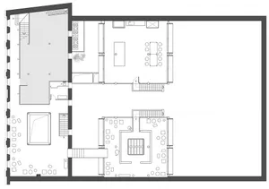 A dimly lit interior space with a mix of rooms, including a dining area and living room, featuring concrete walls, hardwood flooring, and cozy lighting