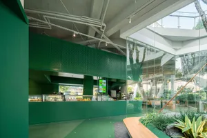 A modern restaurant interior with green walls and flooring, featuring people, dining tables, and potted plants, with a focus on sustainable materials and eco-friendly practices