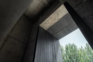 A dark hallway with a concrete floor and walls, leading to an open doorway