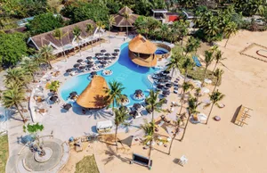 A resort pool surrounded by palm trees and numerous chairs for guests to relax and enjoy the view
