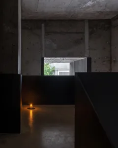 Dimly lit hallway with a black door leading to a second room, visible furniture and flooring
