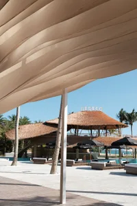 A resort area with palm trees, umbrellas, and chairs creating a relaxing seating arrangement