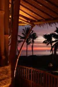 An open-air living area with a bamboo structure, wooden deck, and natural elements creating a warm and inviting atmosphere