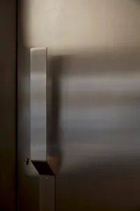 A doorway with a stainless steel door and metal frame, leading into a hallway with a sense of depth and dimension