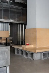Empty restaurant interior with wooden walls and floors, featuring chairs and a red cup on a table, with a clean and inviting atmosphere