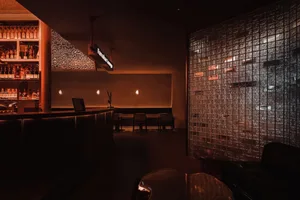 Warm and inviting restaurant interior with wood and glass elements, featuring a dining table, chairs, and a couch
