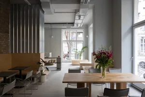 A modern dining space with a table surrounded by chairs, decorated with flowers and potted plants, set in a well-lit room with a welcoming atmosphere