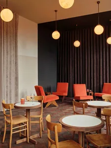 A modern restaurant interior with black walls, tables, chairs, and couches arranged in a comfortable dining area