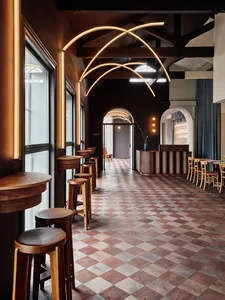 Cozy restaurant with a wooden floor, black walls, and chairs arranged around dining tables in various positions throughout the space