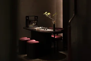 A small kitchen area with a dining table surrounded by chairs, featuring a vase and two cups, creating a cozy and inviting atmosphere