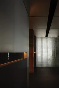 A calm and quiet interior hallway with a modern design featuring a glass block wall, a bench, and a focus on architectural elements