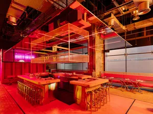 A modern restaurant with red walls, white surfaces, and multiple seating areas with chairs and dining tables