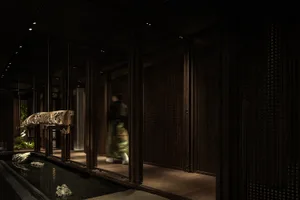 A woman walks down a wooden hallway with two doors, surrounded by classic architectural details