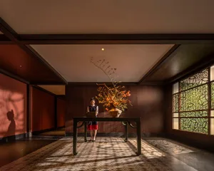 A cozy lobby with a wooden floor, a dining table, chairs, and a vase, creating a comfortable and inviting atmosphere